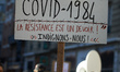 A masked woman holds a placard reads 'Covid-19(84), when injustice becomes the law, rebell...