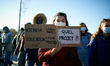 A young woman holds a placard reading 'Interioir Ministry: +1300jobs, Education Ministry -...
