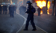 A riot policeman prepares to launch a tear gas canister. Thousands of protesters took to t...