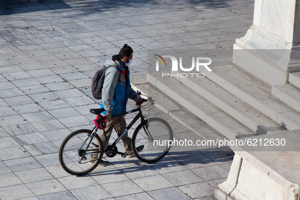 A bicyclist wears a mask at the Syntagma square, in Athens, Greece, on November 23, 2020 amid teh Covid-19 pandemic. 