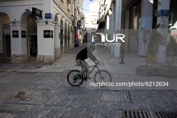 A man cycles at Ermou street in the center of Athens due to lockdown. The SMS code for sport transportation is number 6.  