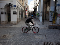 A man cycles at Ermou street in the center of Athens due to lockdown. The SMS code for sport transportation is number 6.  (