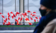 A view of people wearing masks passing by in front of a giant holiday decorations along Si...
