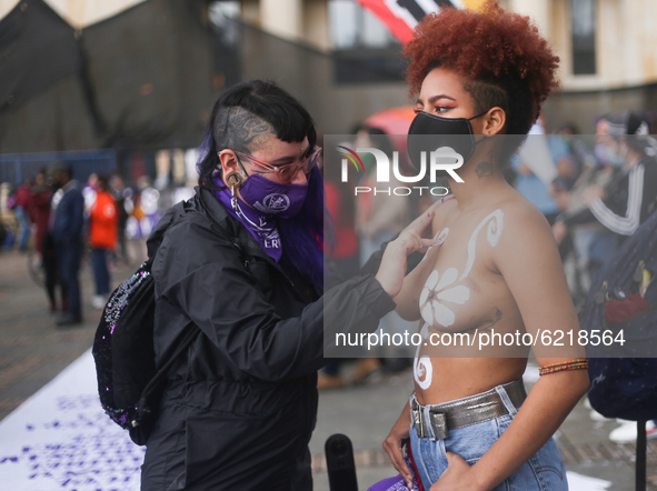 A woman paints another woman on the Day of non-violence against women in Bogota, Colombia, on November 25, 2020 