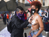 A woman paints another woman on the Day of non-violence against women in Bogota, Colombia, on November 25, 2020 (