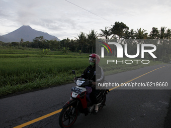 Local residents do activities on the slopes of Merapi mountain as the solfatara smoke spews from the top of Merapi volcano as seen from Yogy...