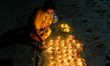 A lady wearing mask lights oil lamp on the day of Dev Deepawali at a river bank in Kolkata...