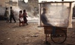 A cake vendor waits for customer inside his polythene wrapped shop as passerby make their...