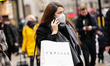A woman wearing a face mask carries a bag from Arcadia-owned clothing retailer Topshop acr...