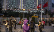 A women wearing a face mask talks to her phone while she stands in front of a China and Ho...