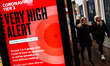 People walk past a notice for 'Tier 3' or 'Very High' alert coronavirus restrictions displ...
