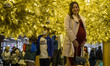 A Pregnant women poses for a photo under a Christmas tree as two boys wearing face mask pl...