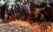 People light up candles outside the Sacred Heart Cathedral on the eve of Christmas celebra...