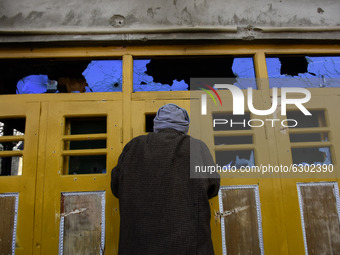 A Kashmiri man looks inside a damaged residential house in Kanigam Village of Shopian district, South of Srinagar, Indian Administered Kashm...