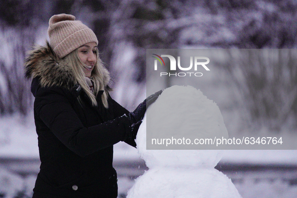 A woman builds a snowman with freshly fallen snow in the Royal Baths park in Warsaw, Poland on January 13, 2021. Though temperatures normall...