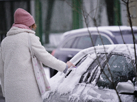 A woman scrapes snow from a car window in the Royal Baths park in Warsaw, Poland on January 13, 2021. Though temperatures normally reach bel...
