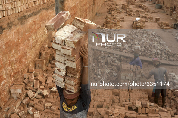A man stacks eighteen bricks on his head while working at in brickfields Narayanganj near Dhaka Bangladesh on January 15, 2021. 