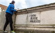 A woman is seen by a 'Gov Have Failed' sign as the UK's government introduced strict Coron...