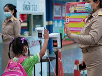 An elementary school student wearing a face mask as a preventive measure have their temperature checked before entering the school at Sri Ia...