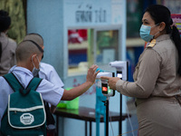 An elementary school student wearing a face mask as a preventive measure have their temperature checked before entering the school at Sri Ia...