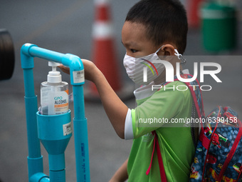 An elementary school student wearing a face mask as a preventive measure have their temperature checked and sanitized their hands before ent...