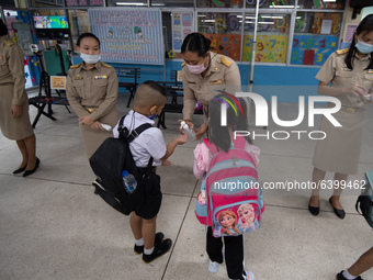 Elementary school students wearing a face mask as a preventive measure received sanitizer gel from a teacher before entering the school at S...