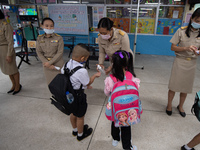 Elementary school students wearing a face mask as a preventive measure received sanitizer gel from a teacher before entering the school at S...