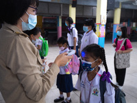 A teacher wearing a face mask checks temperature of a student before entering the school at Sri Iam Anusorn School on February 1, 2021 in Ba...