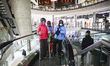 Winter sports enthusiasts wearing ski outfits and carrying ski gear walk inside Forum shop...