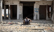 A Palestinian man sit in front of the rubble of buildings which were destroyed during the...