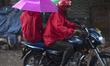 people going to their workplace ride on motorbike during rain in Dhaka 