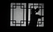 The silhouette of a servant of a house of worship cleaning the windows of the altar room,...