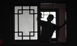 A silhouette of a woman who is a servant of a house of worship cleaning the windows in the...