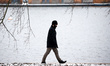 A man wearing a face mask walks through snowfall beside the Serpentine lake in Hyde Park i...