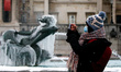 A woman wearing a face mask takes photos near a frozen statue in one of the fountains of T...