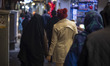 Iranian veiled woman (L) walks hand-in-hand with her female relative along a street-side w...