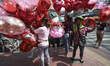 A vendor sells heart-shaped balloons on a street of Valentine's Day at Flower Market Pak K...
