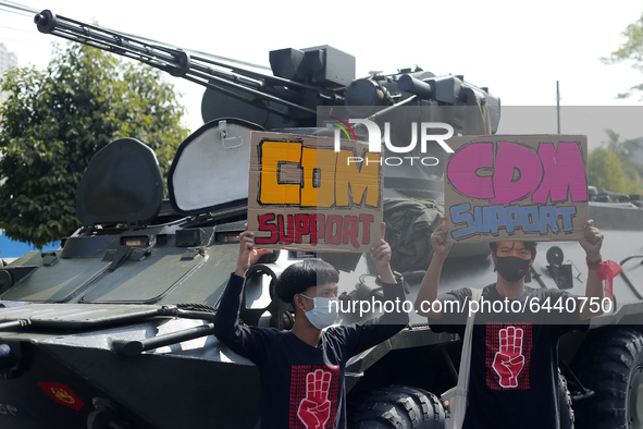 Myanmar protesters hold placards in front of an armoured vehicle during a demonstration against the military coup outside the Central Bank i...