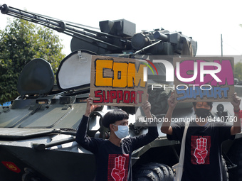 Myanmar protesters hold placards in front of an armoured vehicle during a demonstration against the military coup outside the Central Bank i...