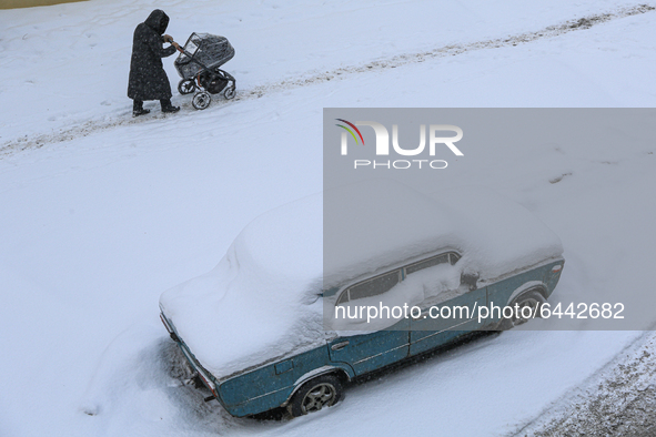A woman with a baby stroller walks down the street after a heavy snowfall in St. Petersburg, Russia, on February 16, 2021. 