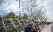 Iranian men use their smartphones as they sit under 5G telecommunications equipment on a M...