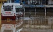 A resident wade through flood water as a bus is partially submerged by flood water after h...