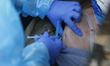 A health worker with gloves administers a COVID-19 vaccine to a senior citizen on a car on...