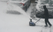 Man uses a snowblower to clear his driveway as a snowstorm dropped 10-15 centimeters of sn...
