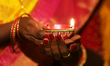 Hindu devotee holds a diya (small clay lamp) during the festival of Diwali at a Hindu temp...