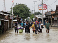 Residents crossing the floods in Pebayuran sub-district, Bekasi regency, West Java, on February 22, 2021. Massive floods hit a number of vil...