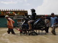 a woman sit on her motorbike carried by a cart service as she crosses the flood in Pebayuran sub-district, Bekasi regency, West Java, on Feb...