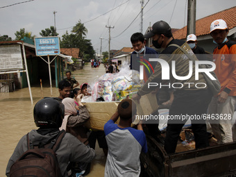 Residents unload logistics from the truck during floods in Pebayuran sub-district, Bekasi regency, West Java, on February 22, 2021. Massive...