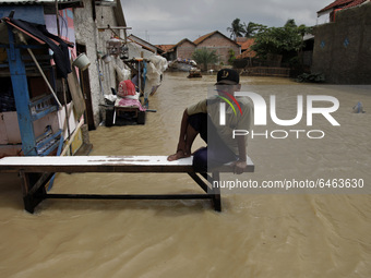 An elderly man sits on the wooden chair amid floods in Pebayuran sub-district, Bekasi regency, West Java, on February 22, 2021. Massive floo...
