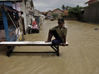 An elderly man sits on the wooden chair amid floods in Pebayuran sub-district, Bekasi regency, West Java, on February 22, 2021. Massive floo...